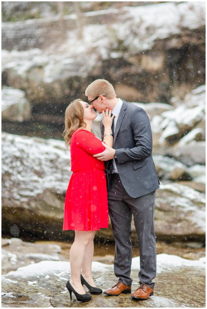 Snowy engagement session on the rocks in front of the waterfall at Babcock State Park in West Virginia.