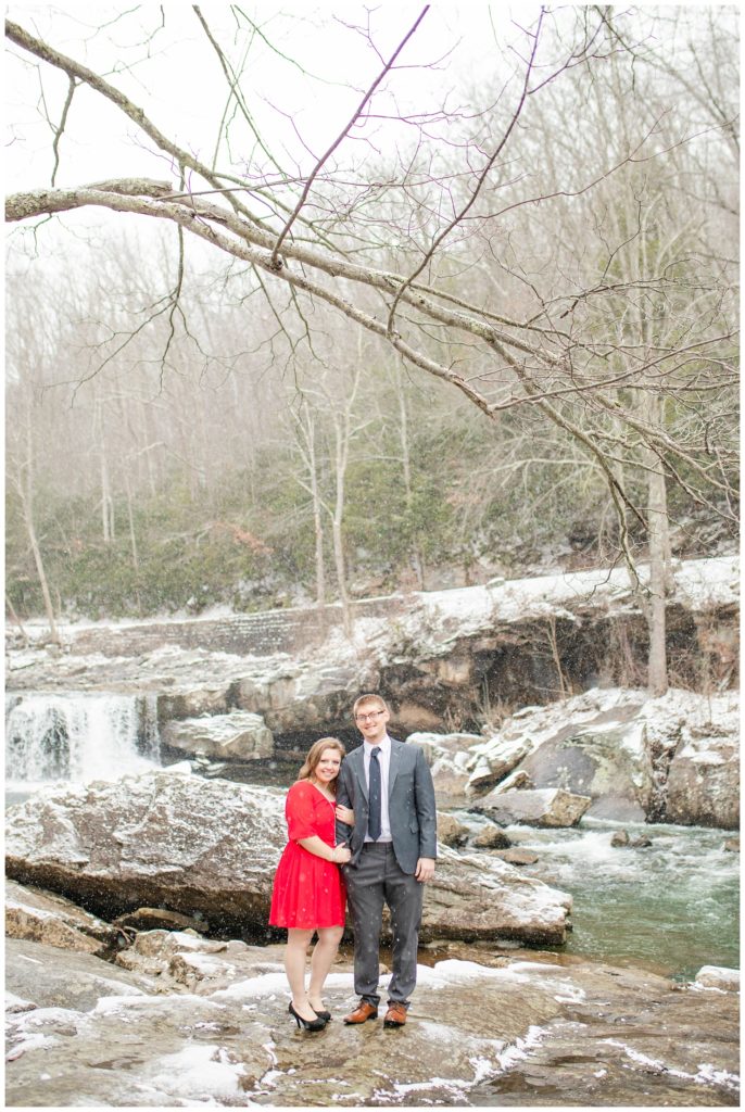 Snowy engagement session on the rocks in front of the waterfall at Babcock State Park in West Virginia.