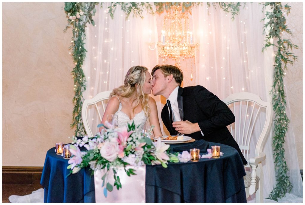 Bride and Groom kiss during wedding toasts at their sweetheart table at The Venetian Estate, formerly known as Maylon House, in Milton, WV