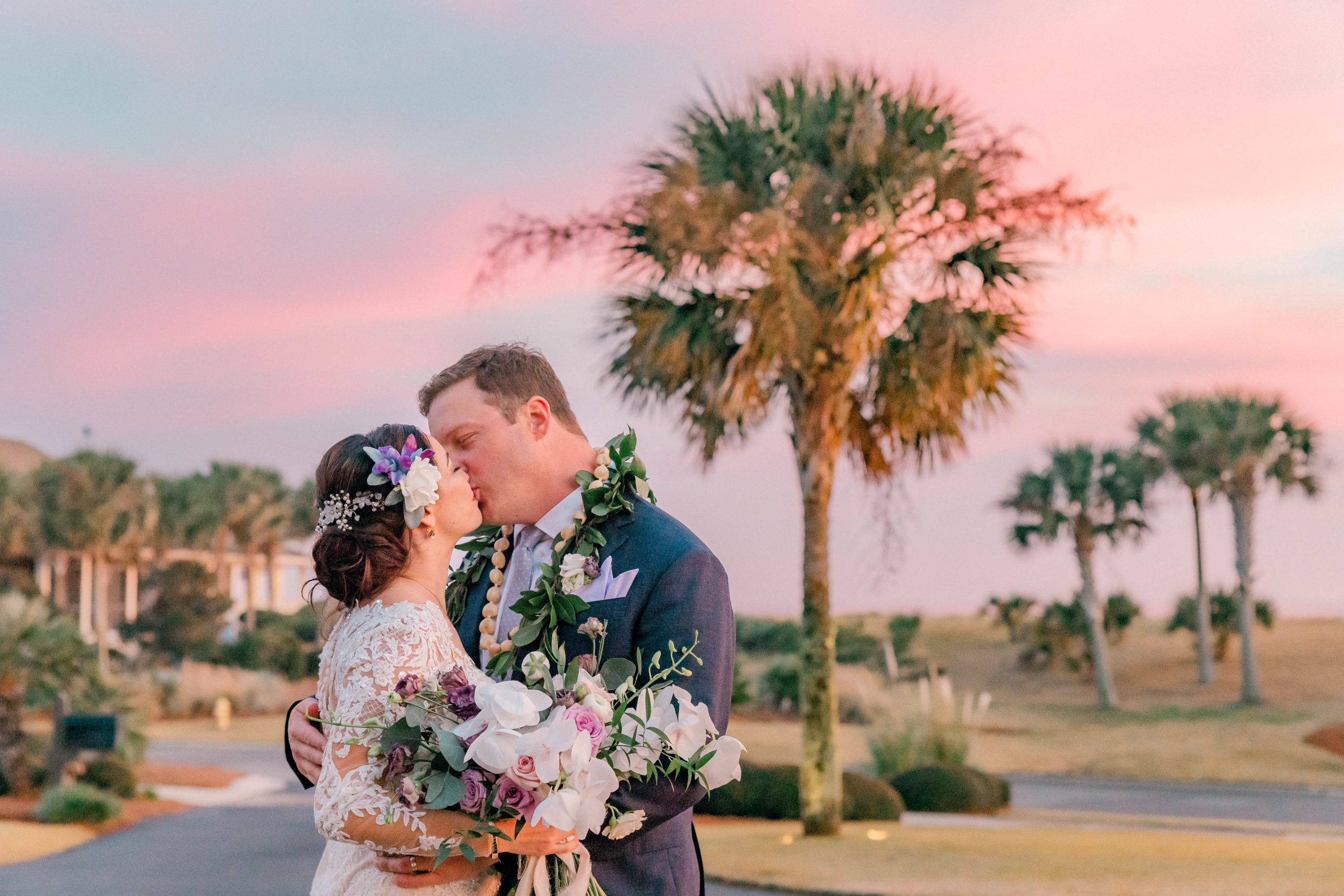 Newlyweds kiss under pink and purple clouds at Seabrook Island Beach Club Wedding