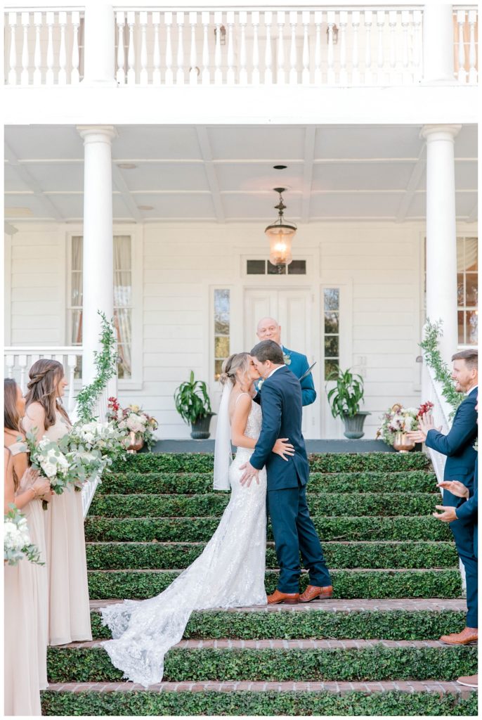 Newlyweds share first kiss during their ceremony in front of Old Wide Awake, a wedding venue in Charleston, SC