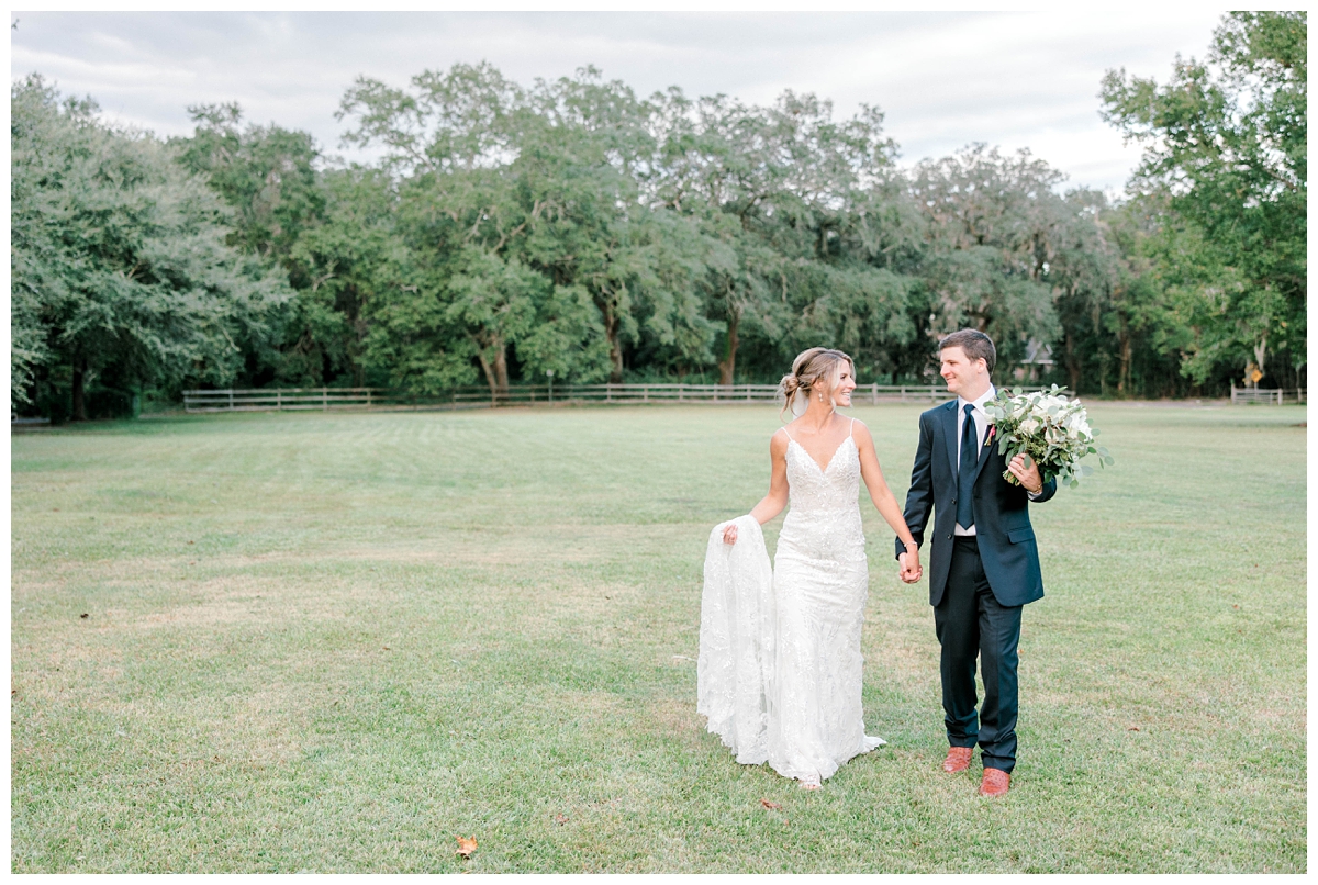Newlyweds walk during photos in a field outside their wedding venue in Charleston, SC