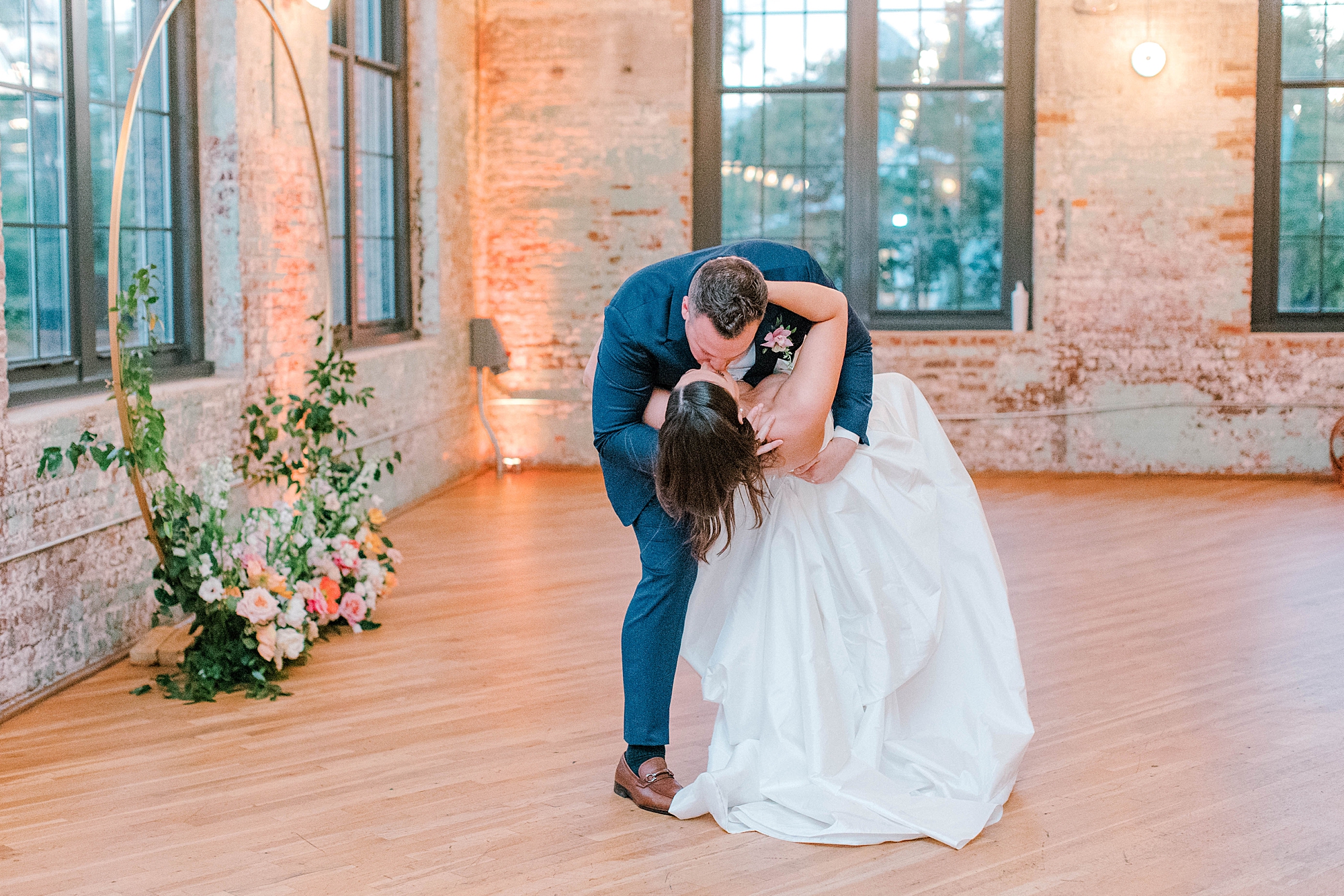 groom dips bride kissing her in corner of brick lined room at The Cedar Room