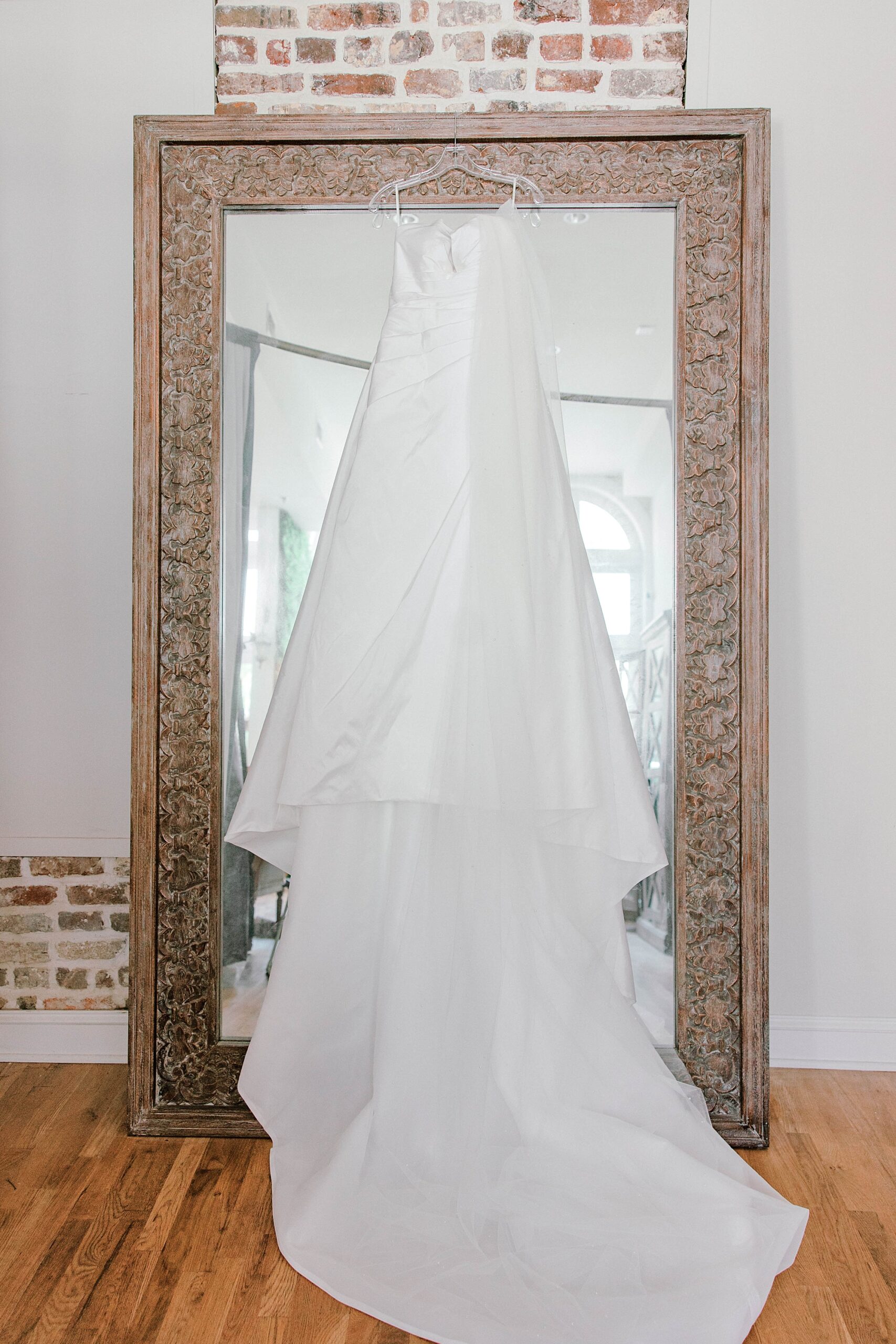bride's dress hangs on mirror inside Lashes & Lace