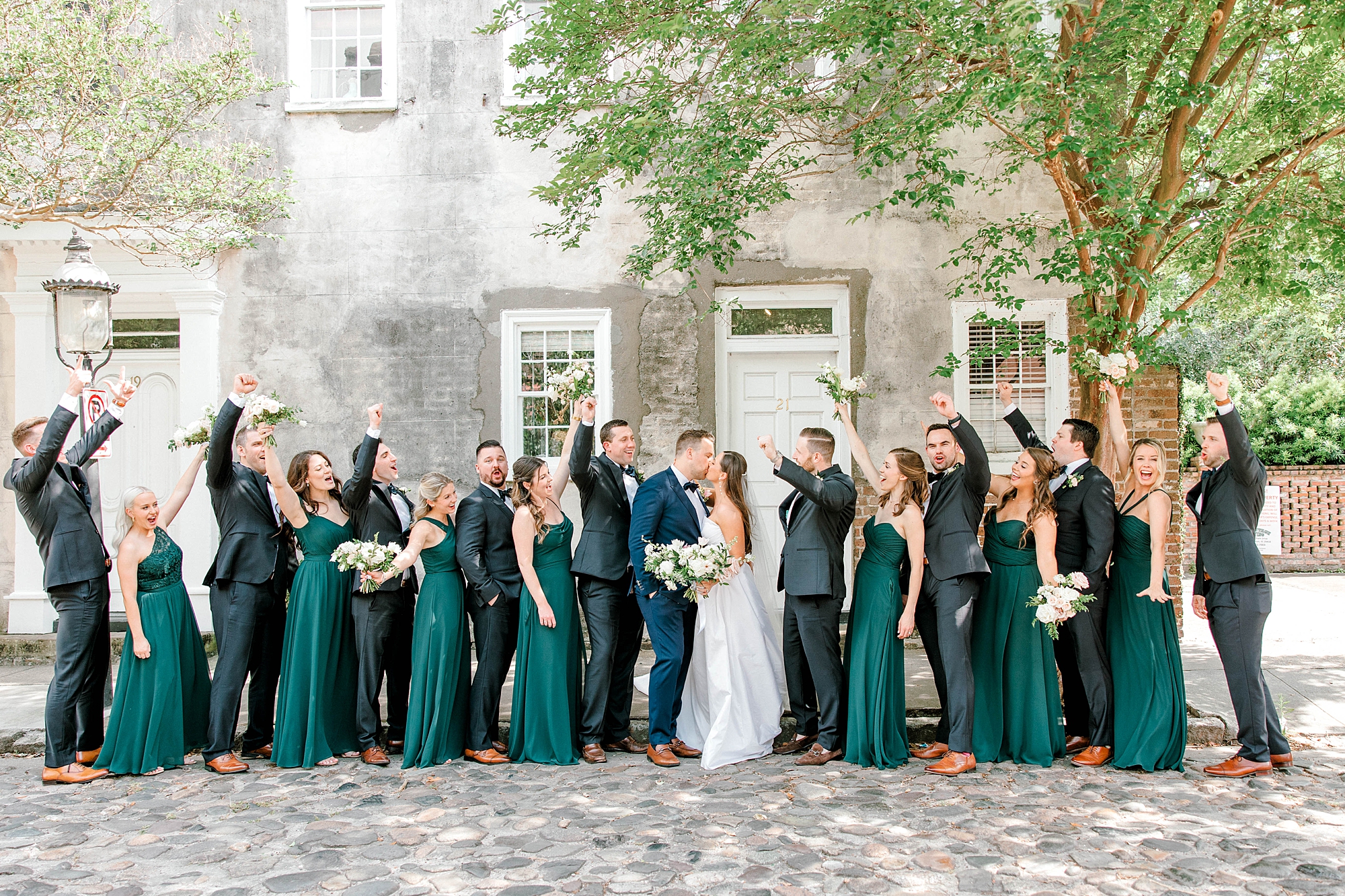 bride and groom kiss while wedding party cheer in Charleston SC