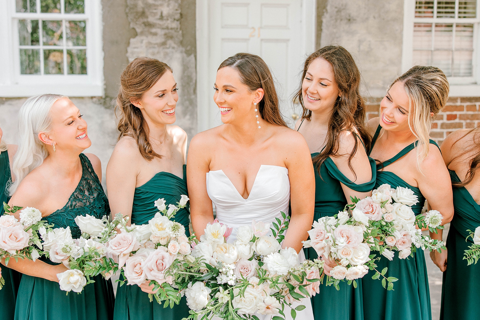 bride laughs with bridesmaids in mismatched forest green gowns 