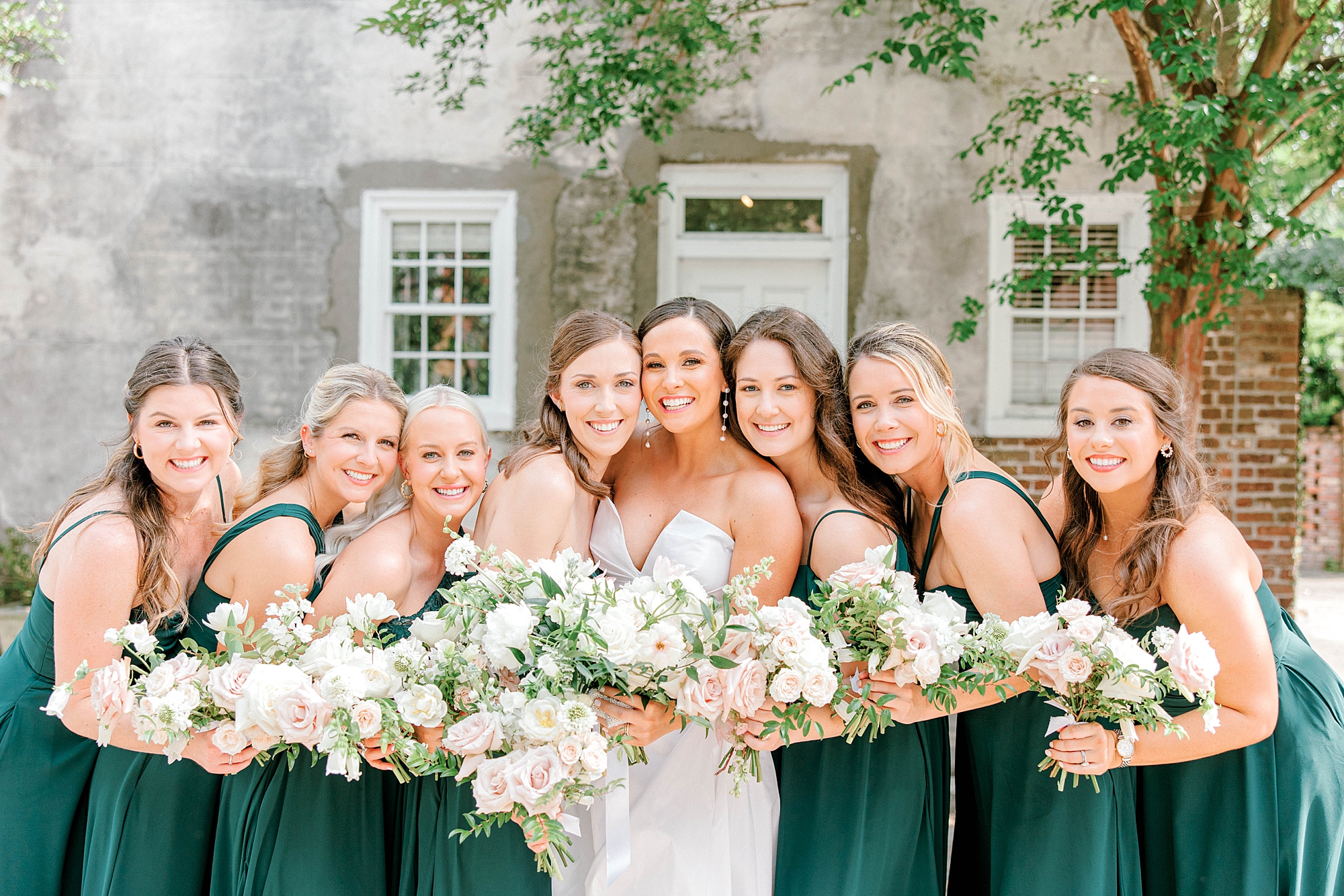 bride hugs bridesmaids in forest green gowns on Charleston street 