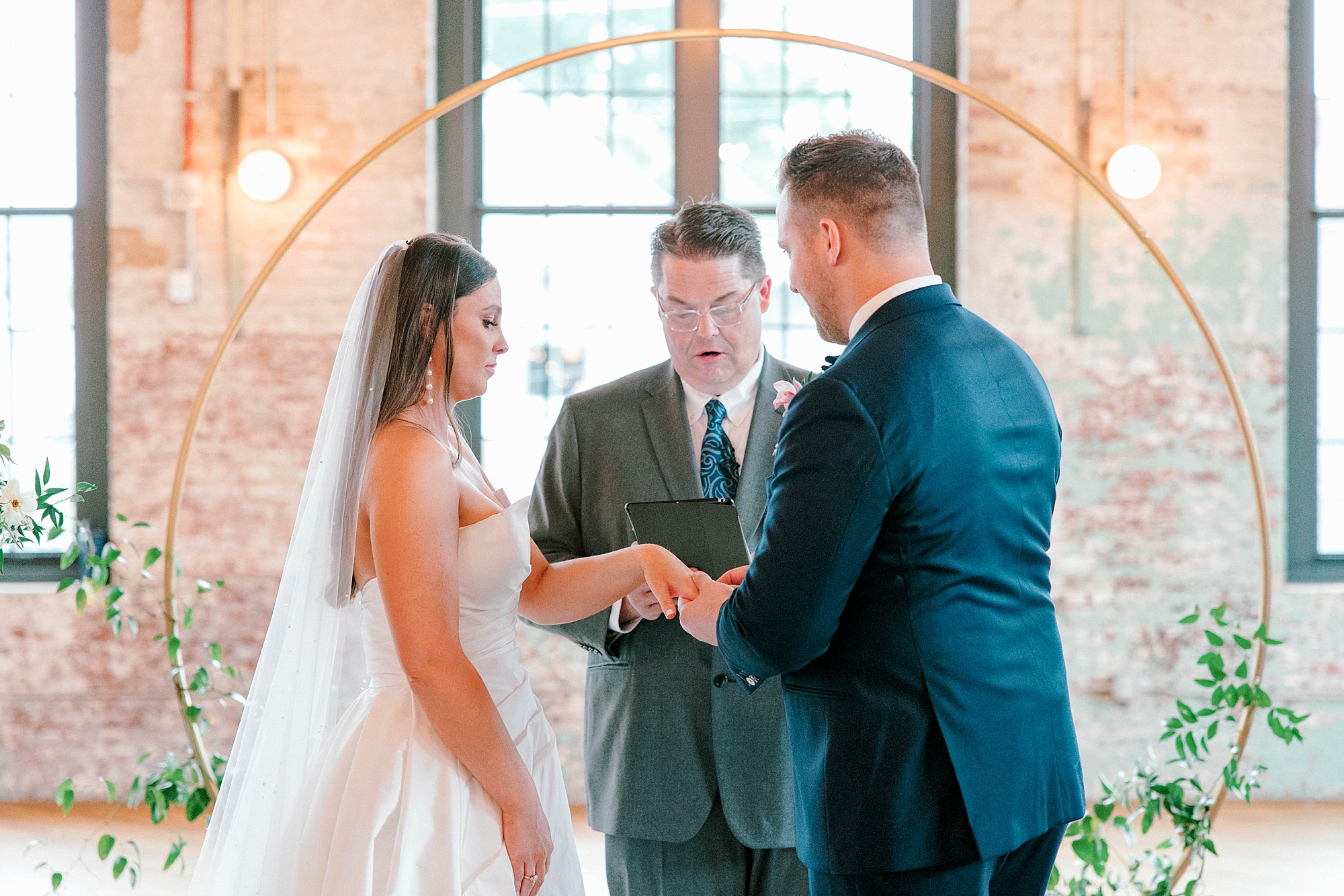 bride and groom exchange vows under gold circular arbor at The Cedar Room