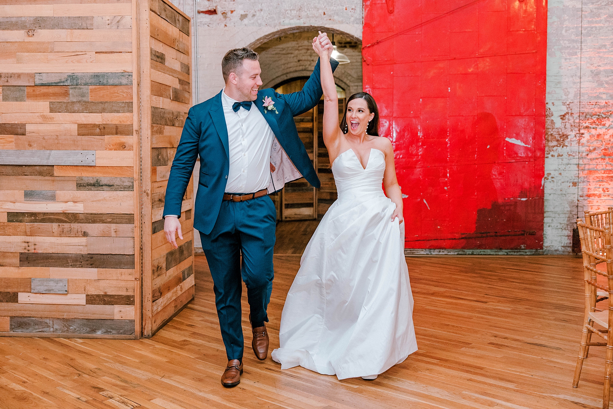 bride and groom cheer holding hands walking into Charleston wedding reception 