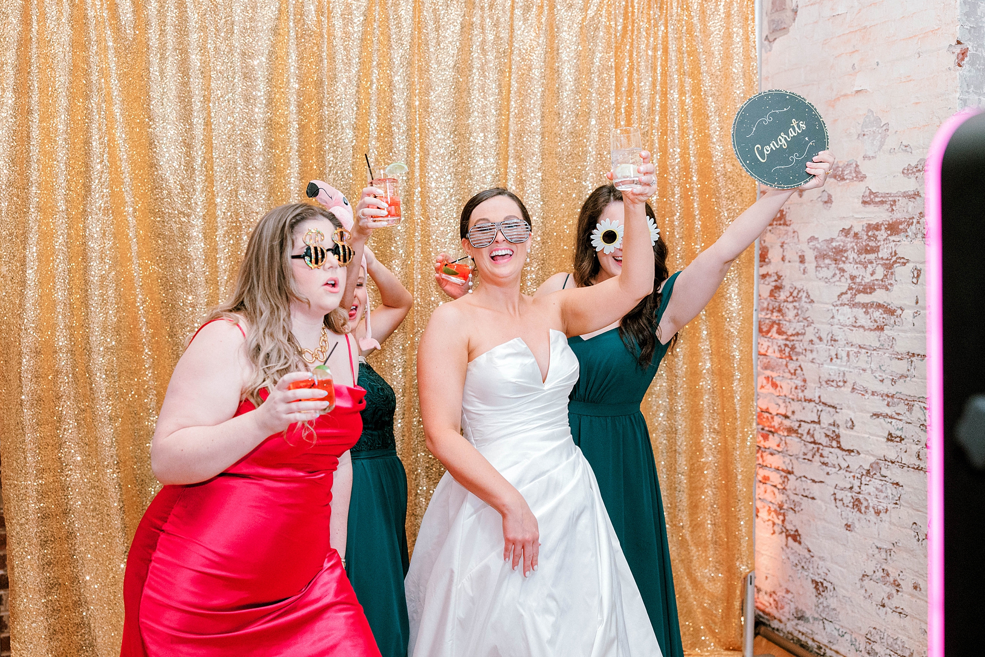 bride poses in photo booth with guests during Charleston wedding reception