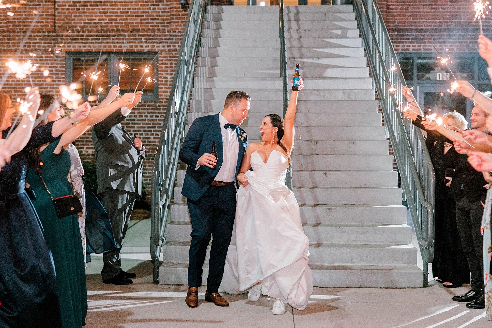 bride and groom cheer during sparkler exit leaving Charleston wedding reception