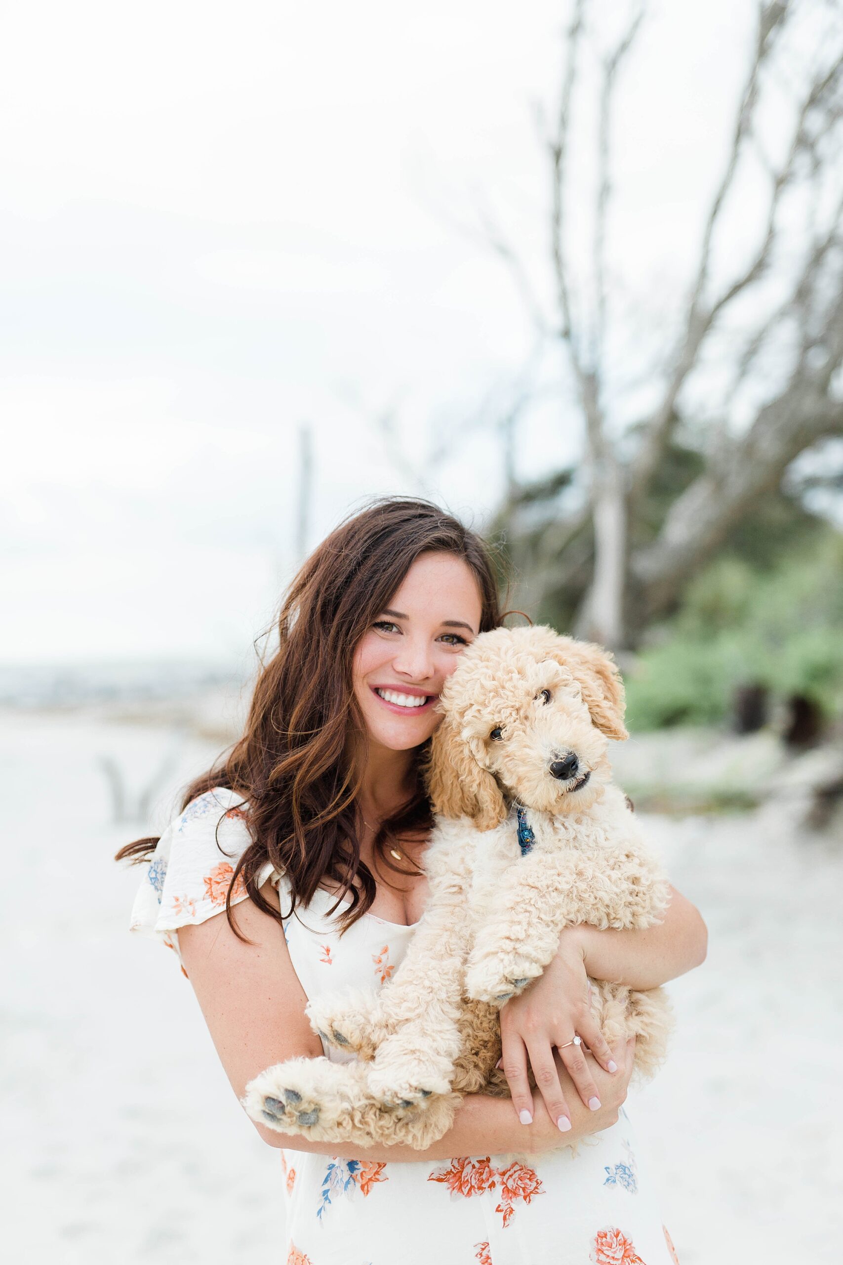 woman holds golden doodle puppy on Charleston beach