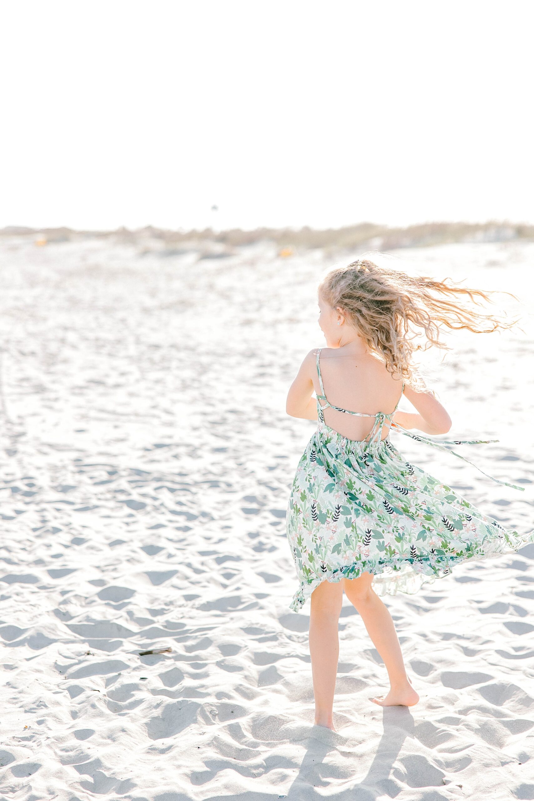 girl twirls on beach during family photos in Charleston SC