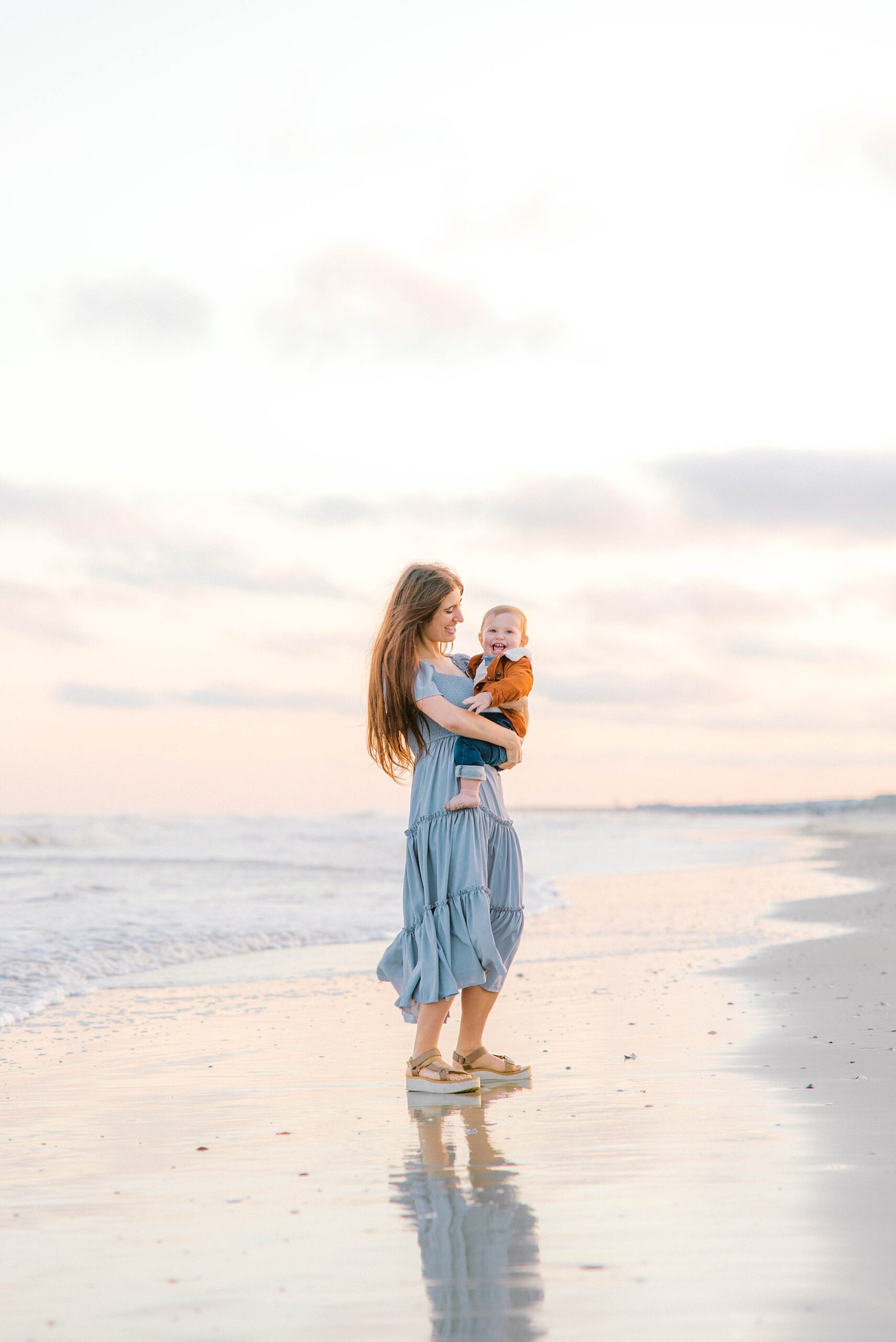 mom stands holding baby on hip during Charleston beach family photos