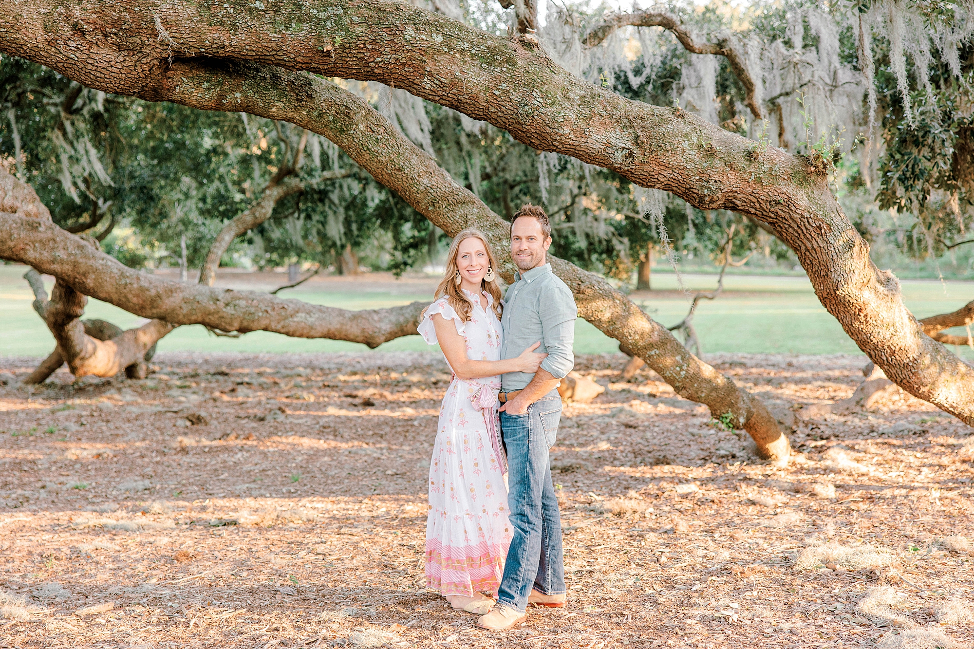 married couple hugs by large tree branches in Charleston park