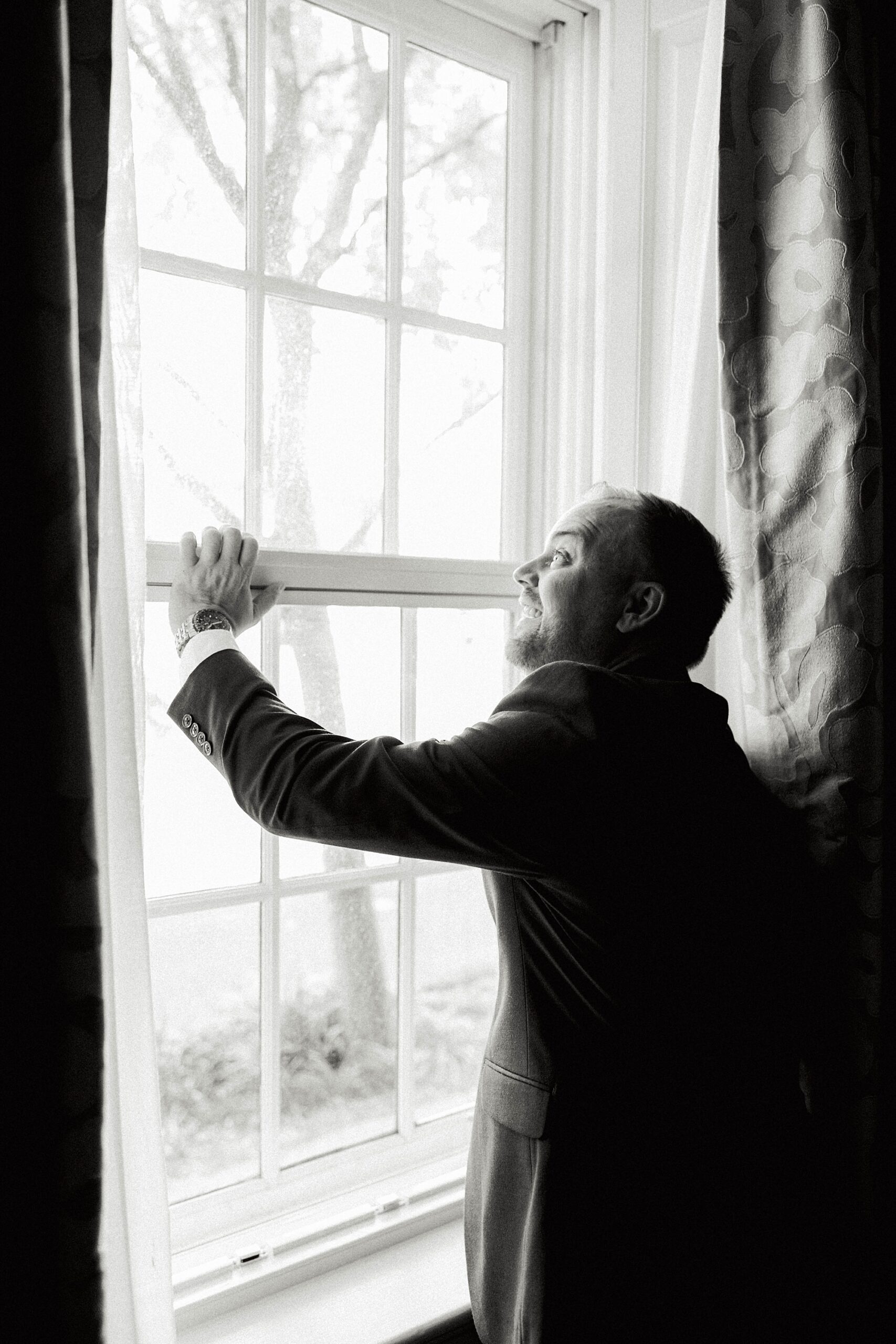 groom leans against window of Planter's Inn