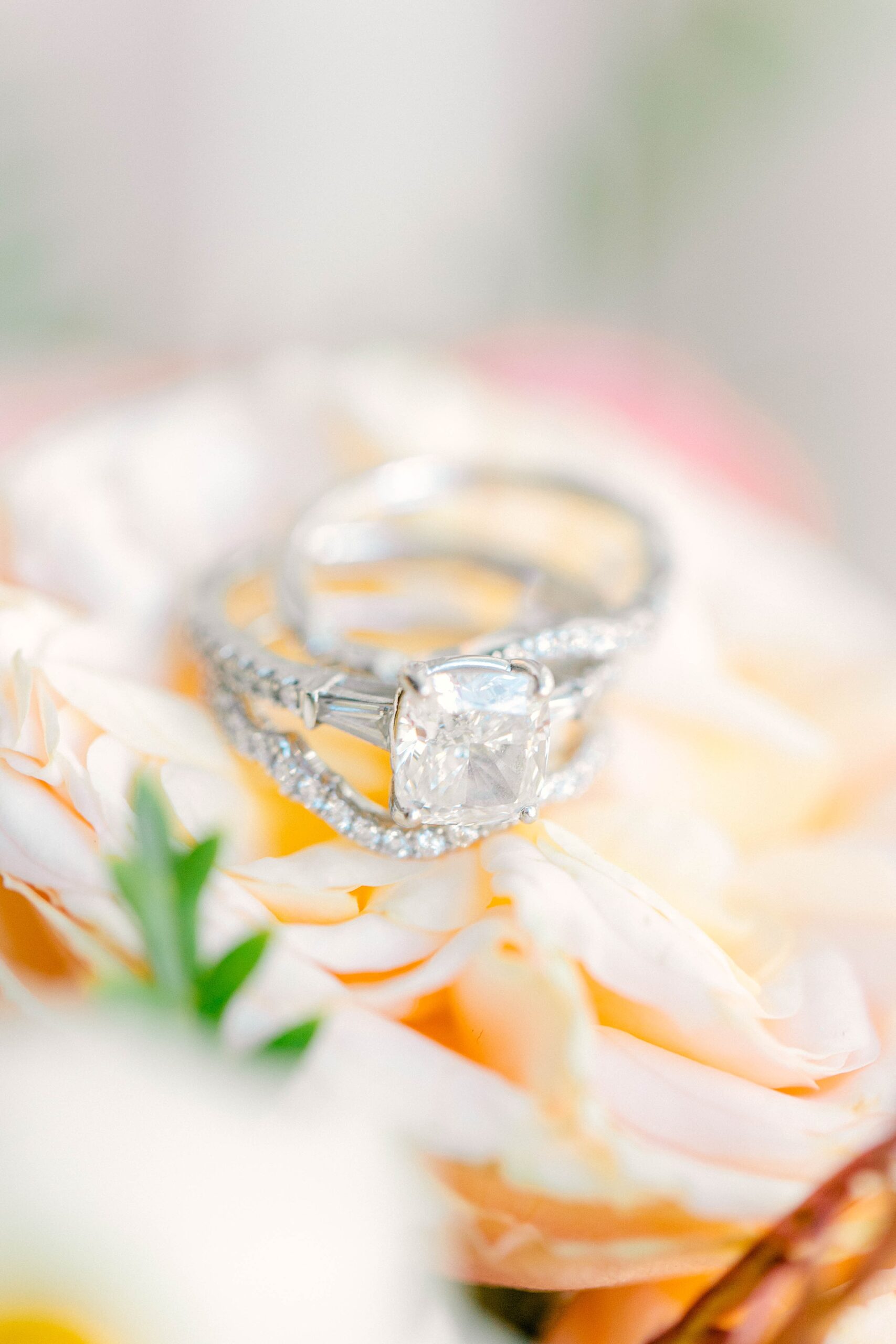 diamond wedding rings rest on white peonies 