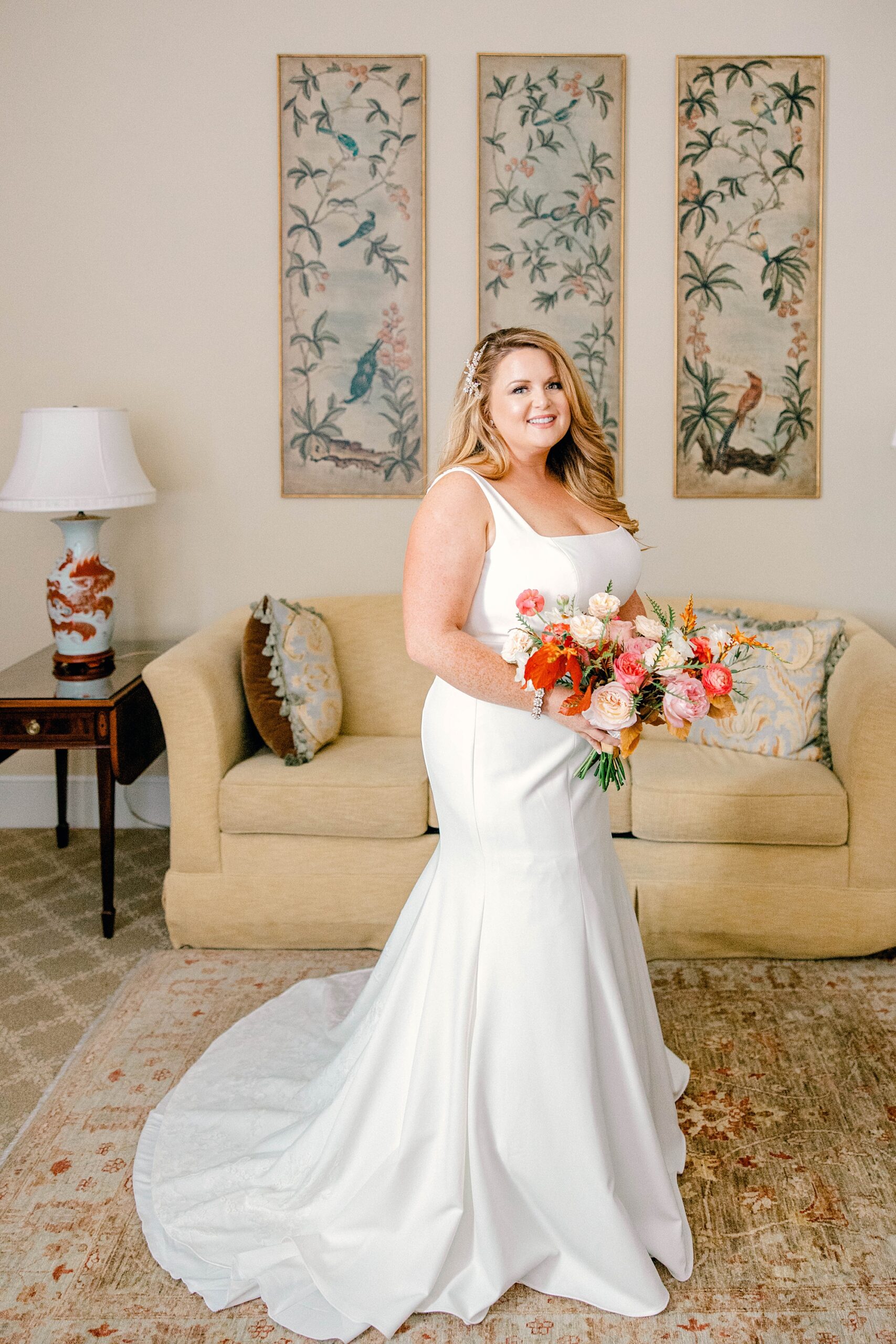 bride stands in hotel room at Planter's Inn in wedding dress with bright bouquet 