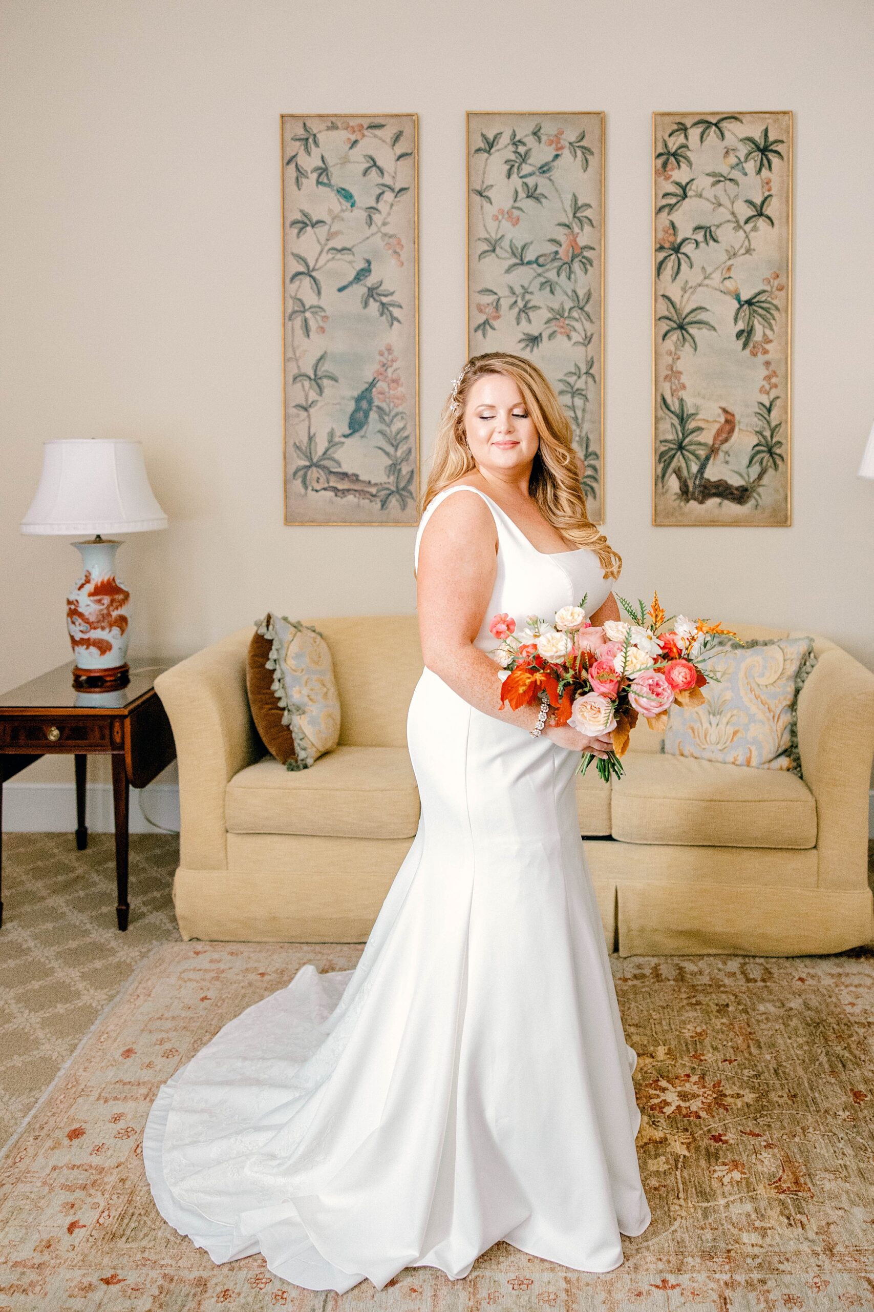 bride stands in room at Planter's Inn with bright bouquet looking over shoulder 