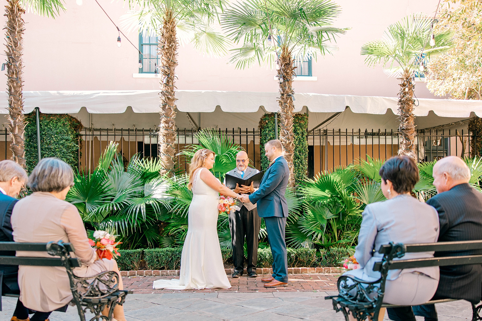 newlyweds hold hands during wedding ceremony in the courtyard at Planter's Inn
