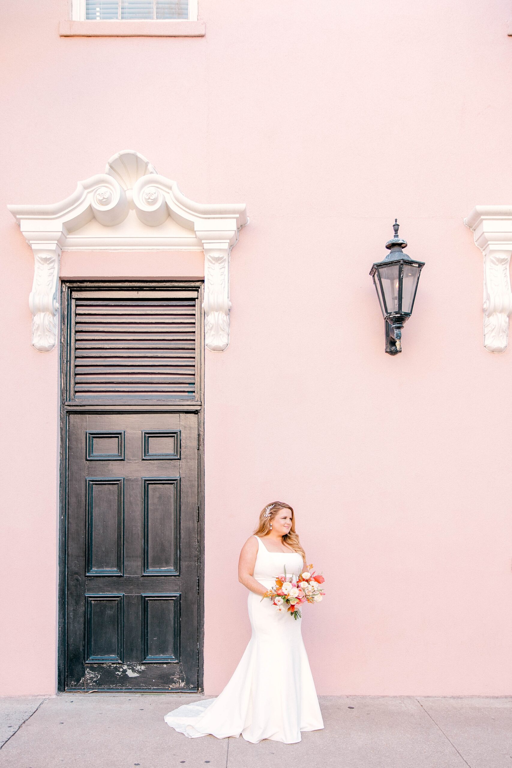 bride poses against pink wall in Charleston SC
