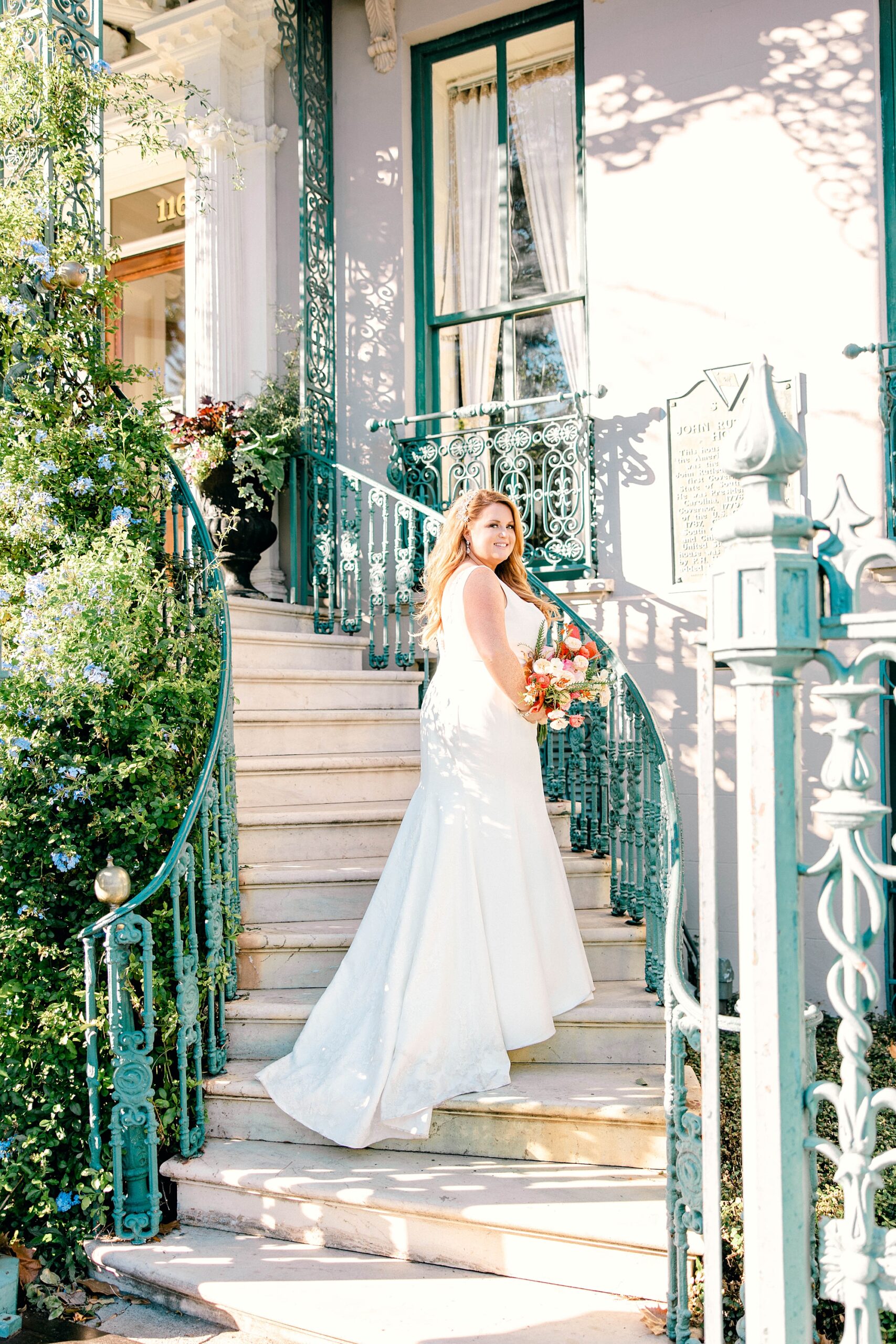 bride poses on spiraling staircase in wedding dress with bright bouquet 