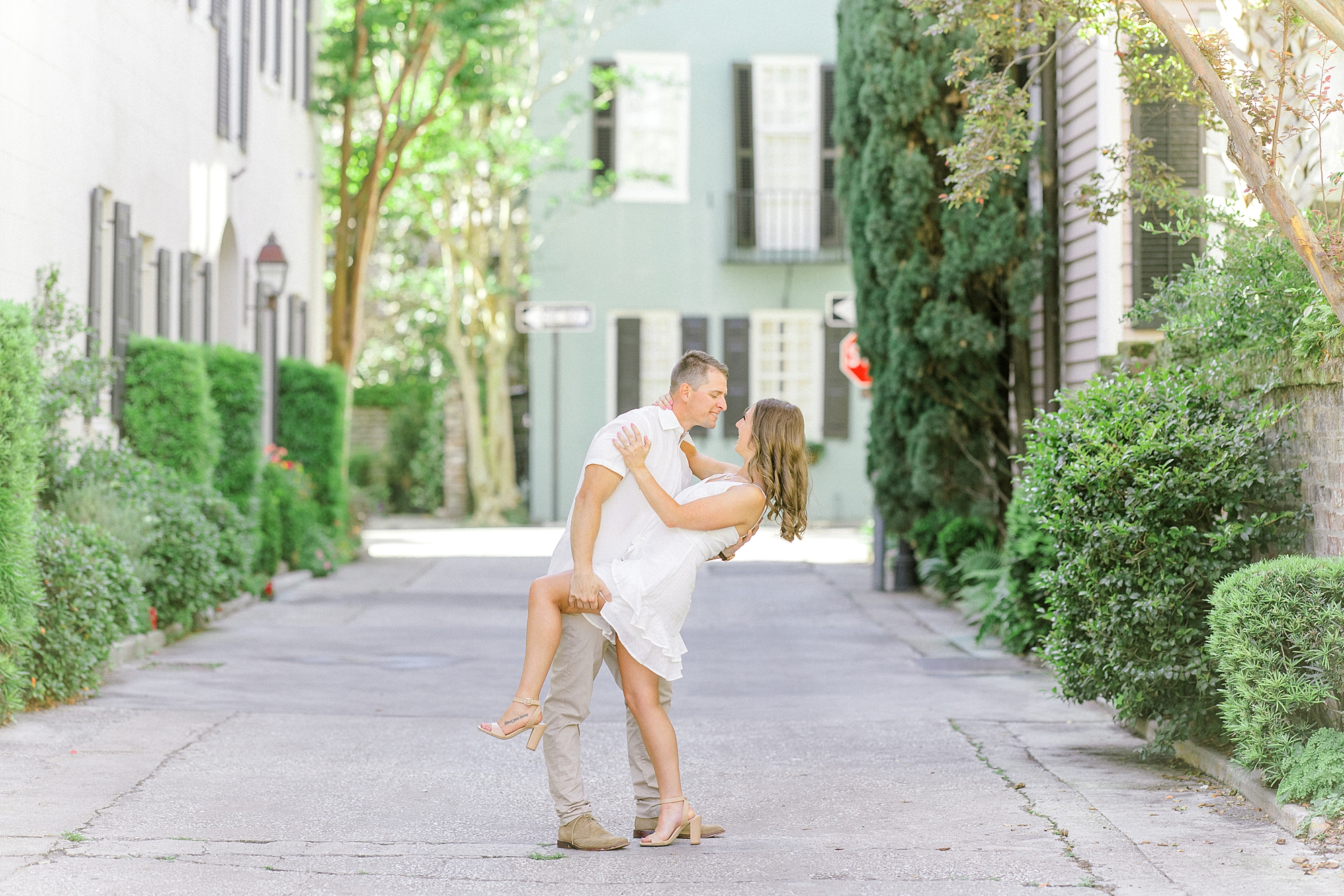 man dips fiancee holding her knee up during Historic Downtown Charleston engagement session