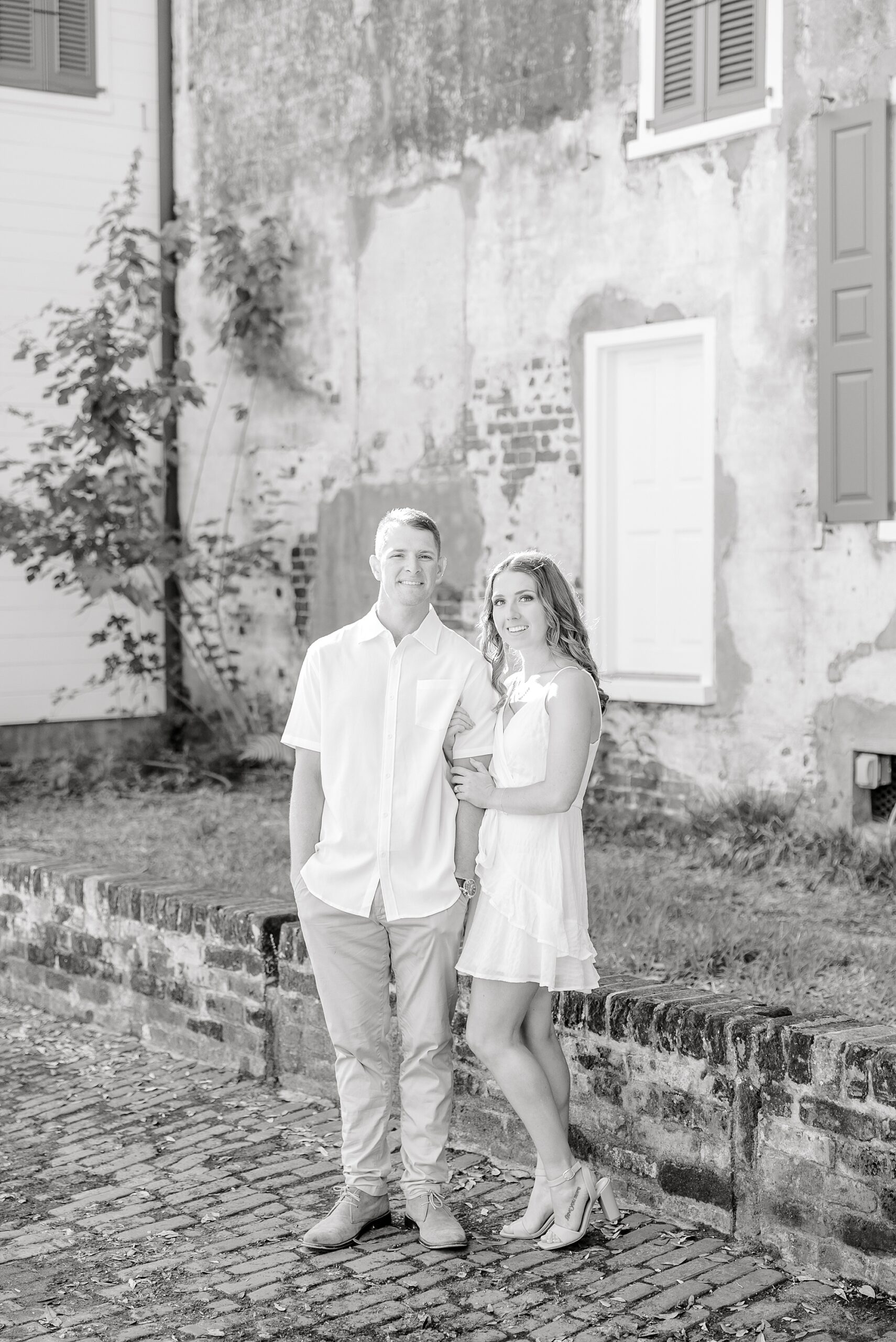 black and white photos of couple posing by stone home in Charleston SC