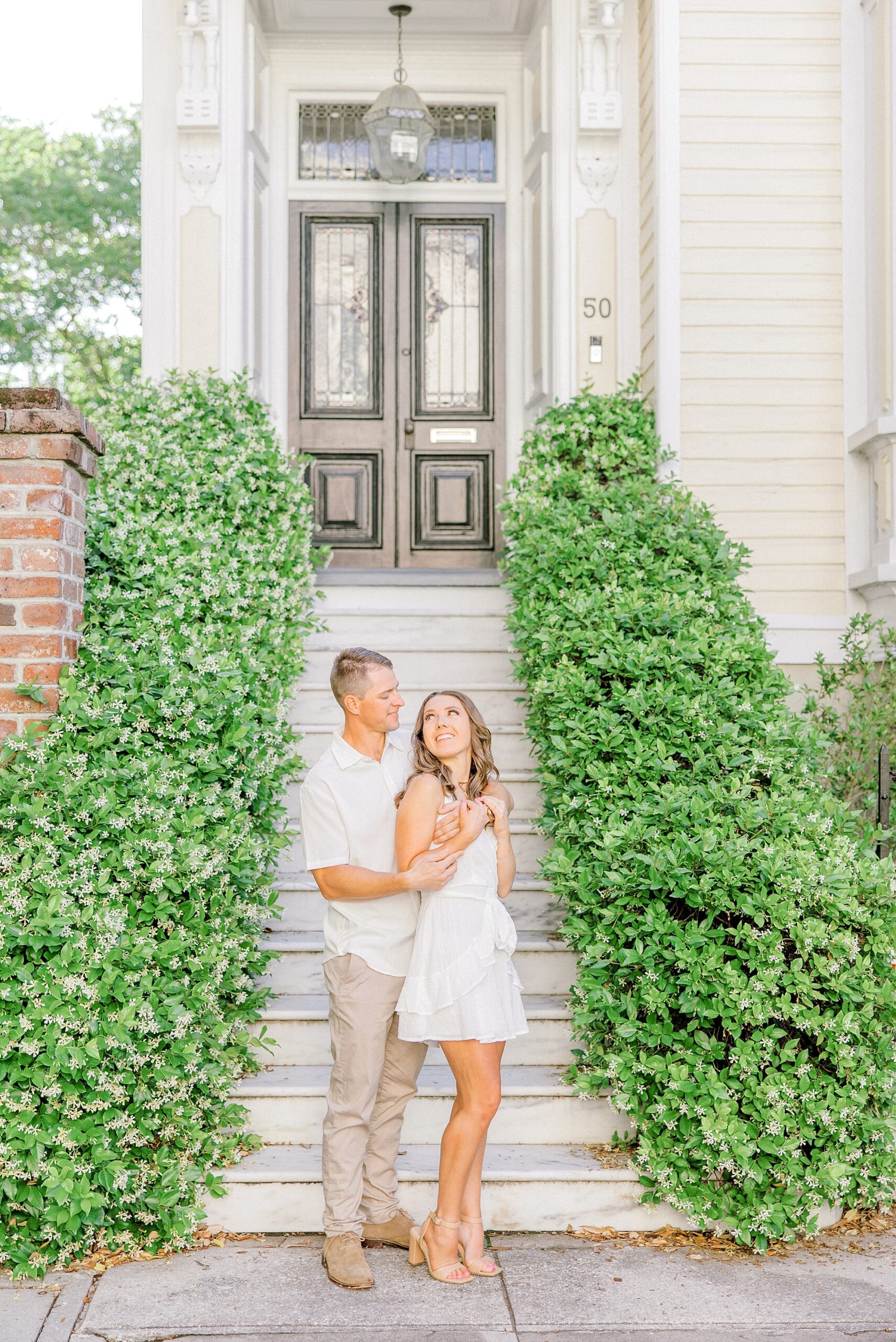 woman leans into man smiling up at her during Historic Downtown Charleston engagement session