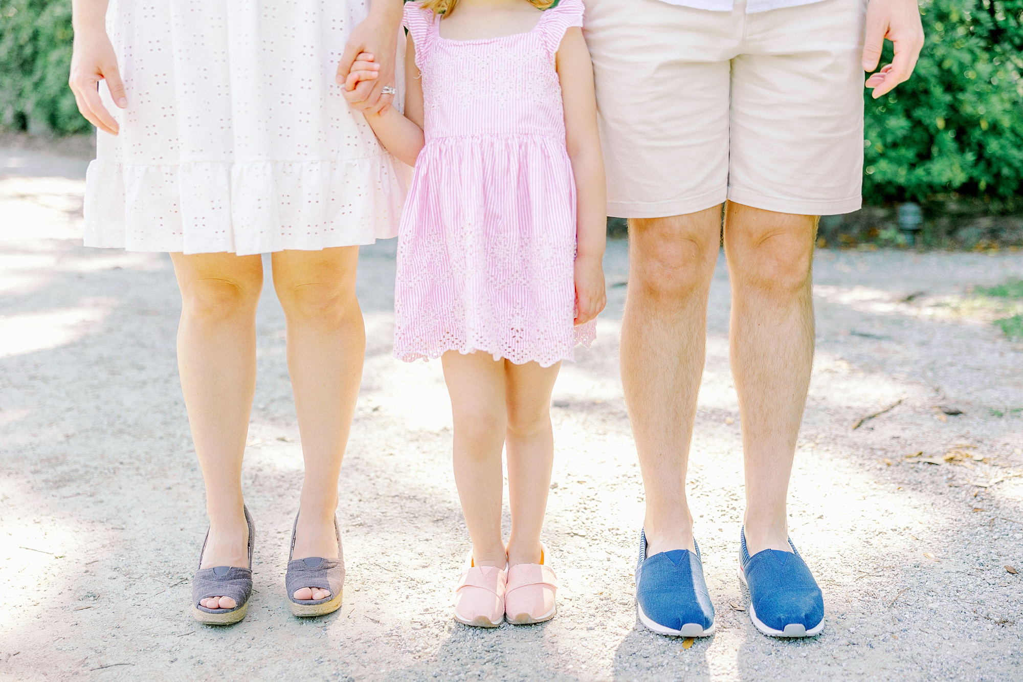 parents pose holding hands with daughter in matching TOMS
