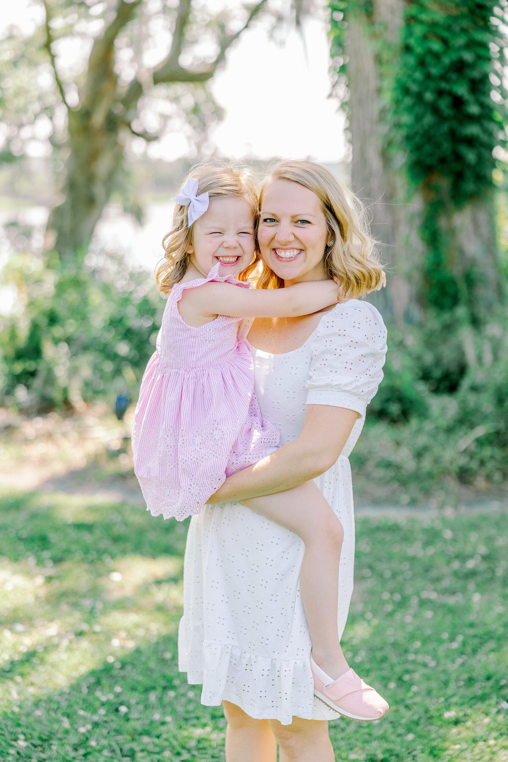 mom in white dress holds four year old daughter in pink dress