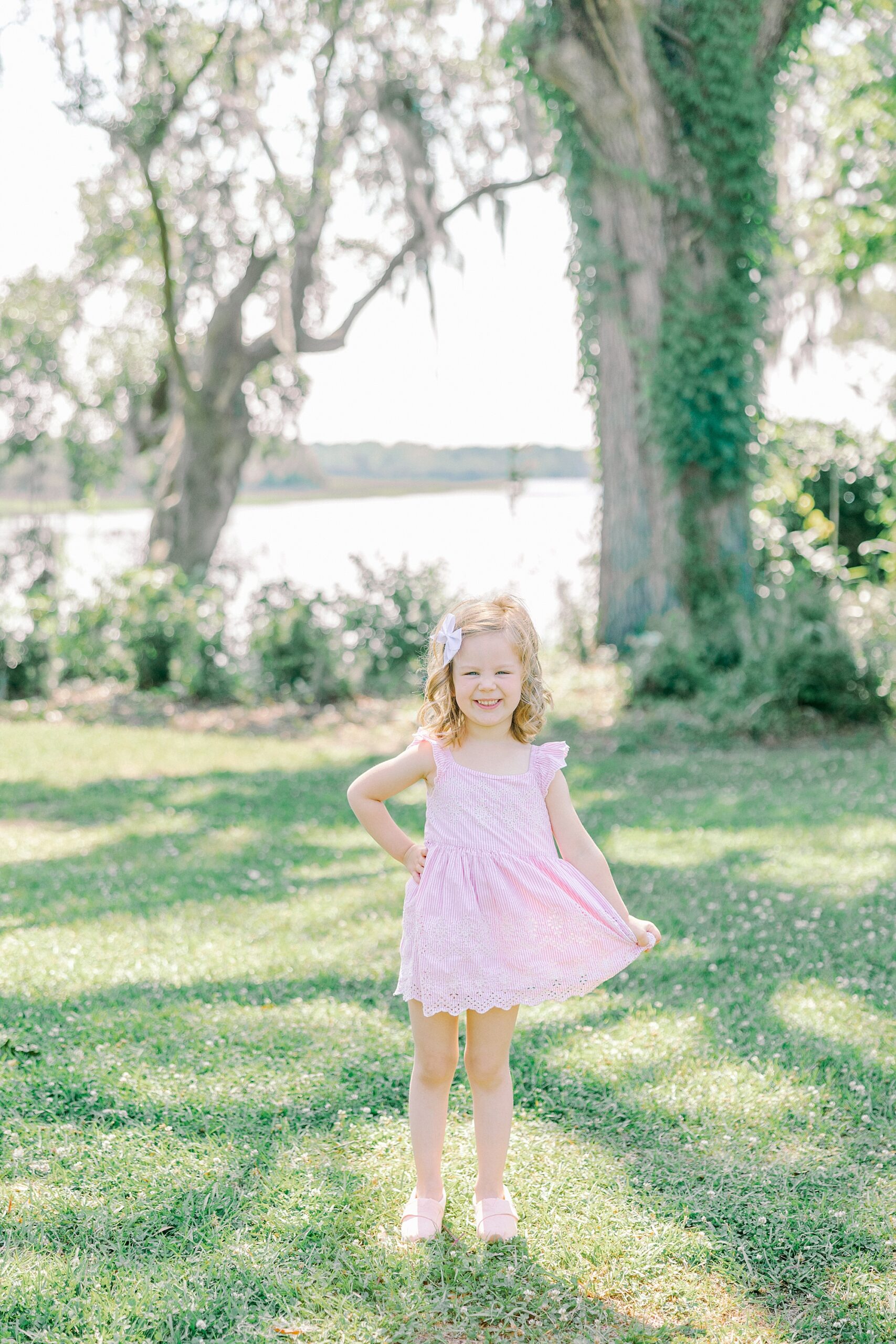 blonde girl poses in pink dress near waterfront in Charleston SC