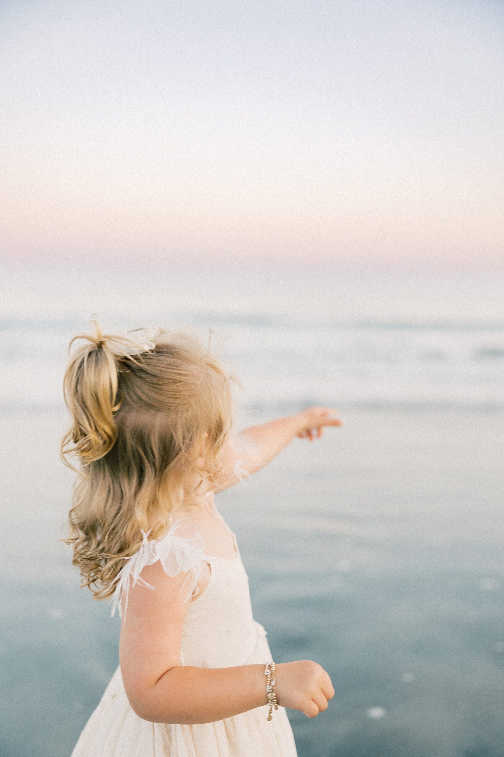 young girl points out to ocean during Folly Beach family portraits