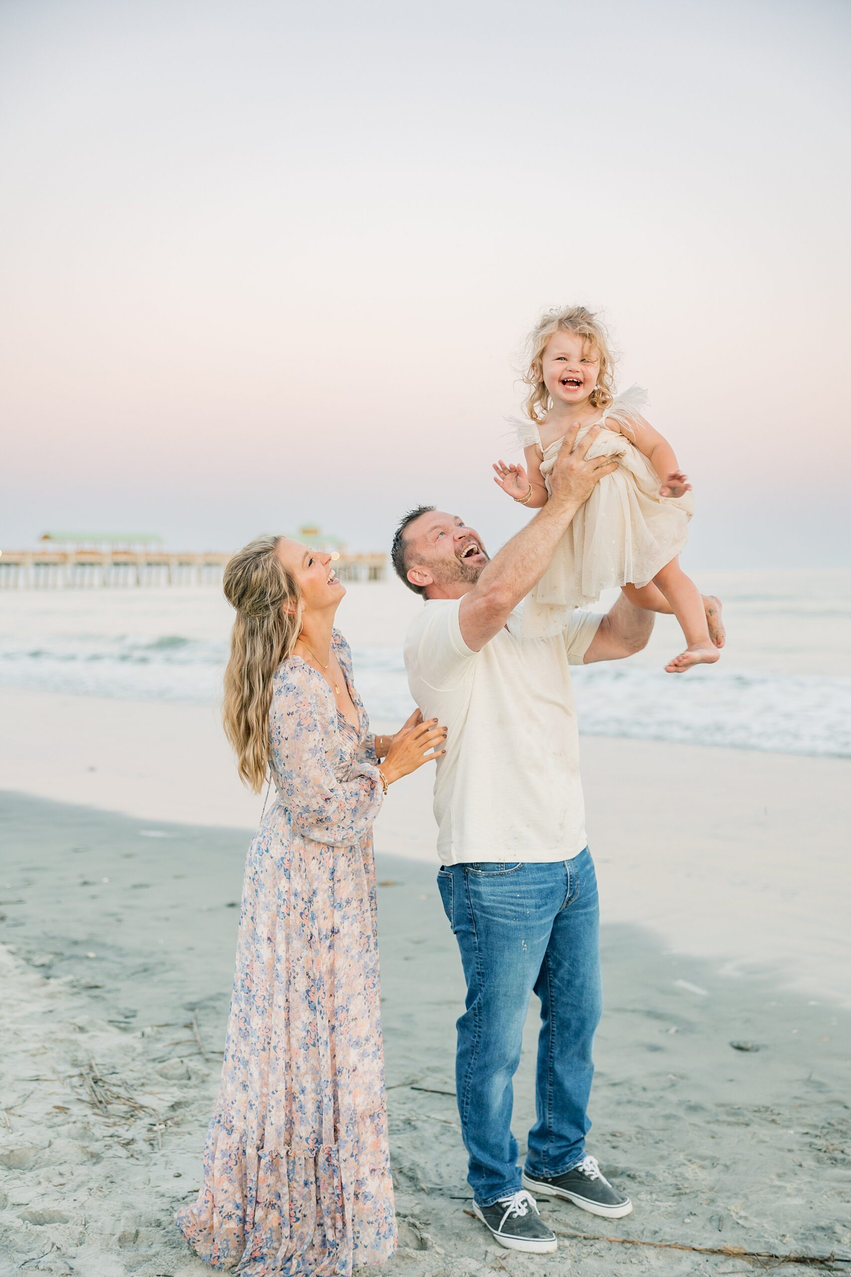 dad tosses toddler in the air during family photos on the beach in South Carolina